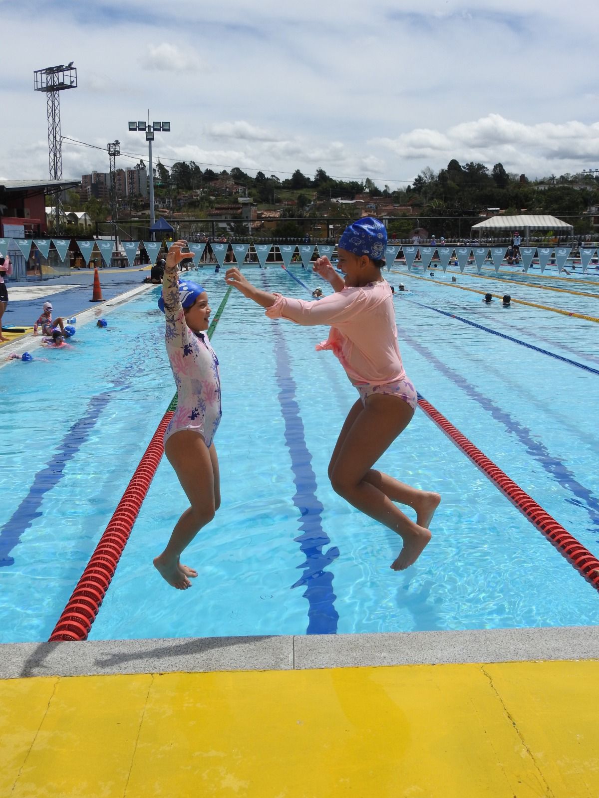 Dos niñas saltando felices a la piscina
